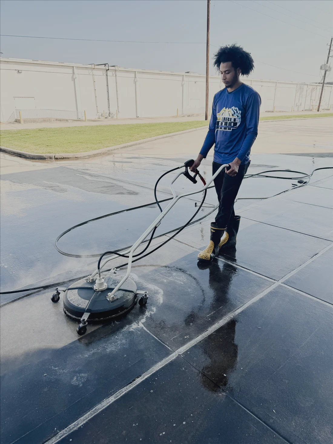 A Double Tap technician pressure-washing a driveway