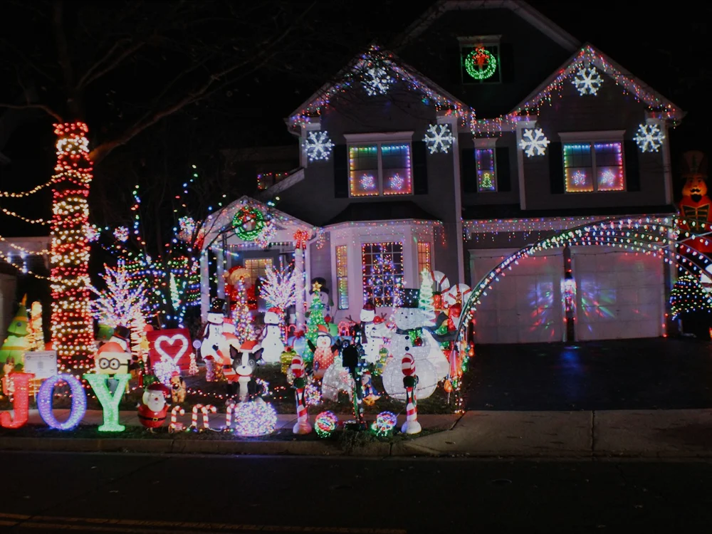 A suburban home decorated with Christmas lights at dusk.