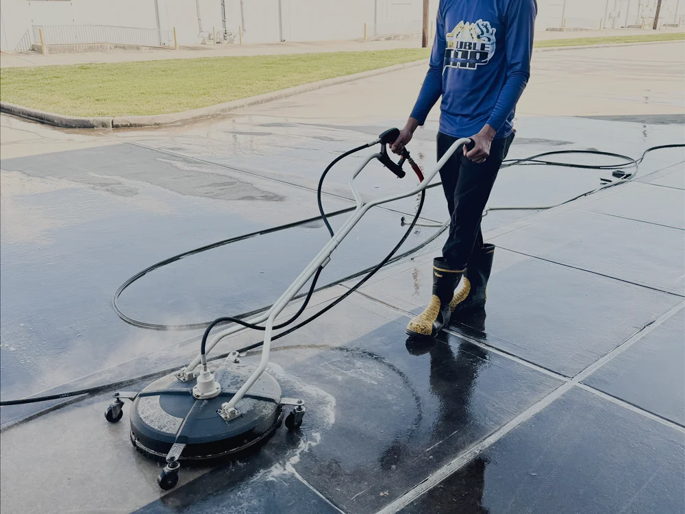 A technician running a surface cleaner across wet concrete flatwork.