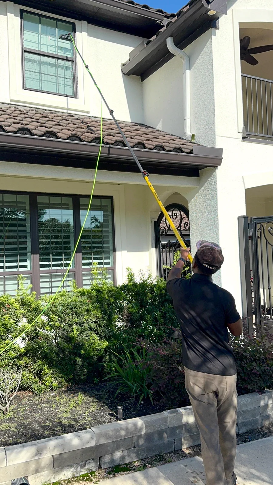 Double Tap technician cleaning upper windows with a water-fed pole