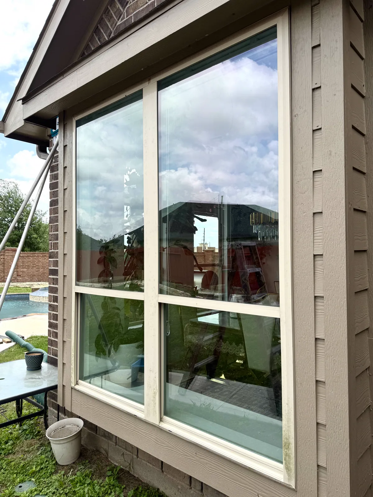 Clean exterior window reflecting sky and pool during a Double Tap service